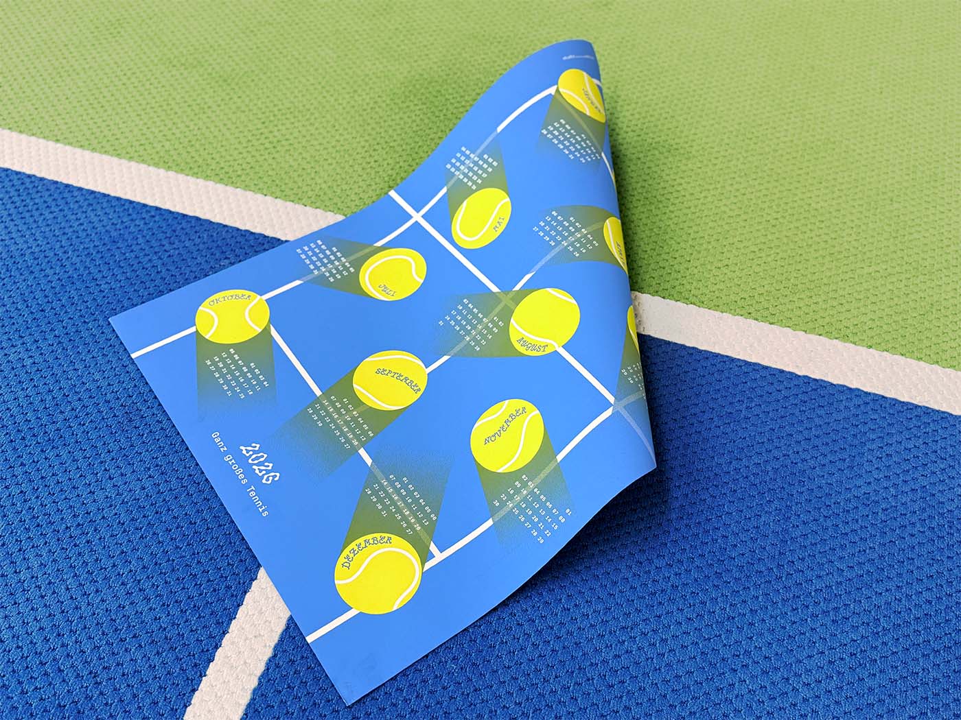 Full view of the 2026 studio_upstruct calendar, half-rolled on a tennis court.