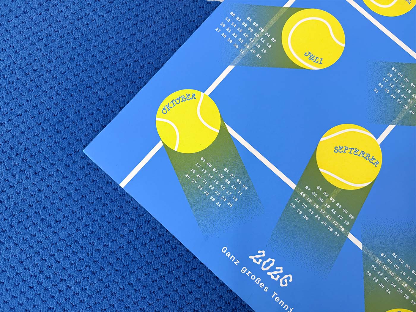 Close-up of the 2026 studio_upstruct calendar on a blue tennis court, showing a few months and the calendar title, '2026 – Ganz großes Tennis.'