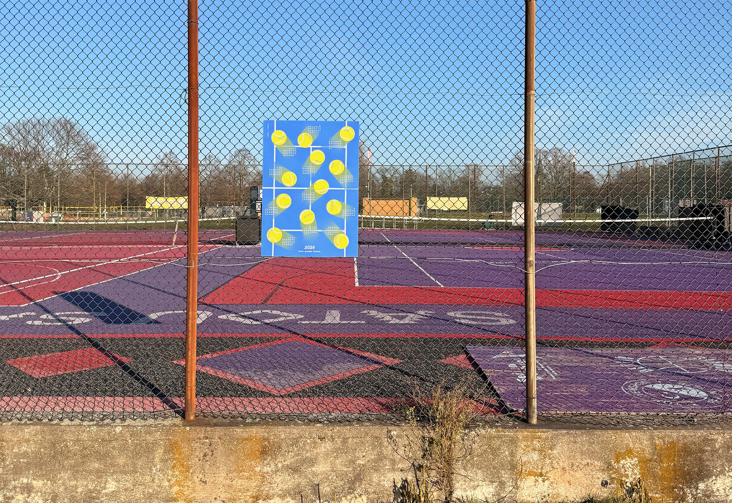The 2026 studio_upstruct calendar is hanging on the fence of a tennis court.